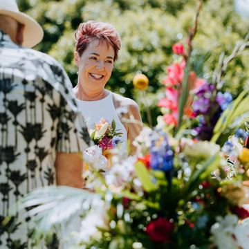 The bride laughing with guests behind colourful wedding flowers