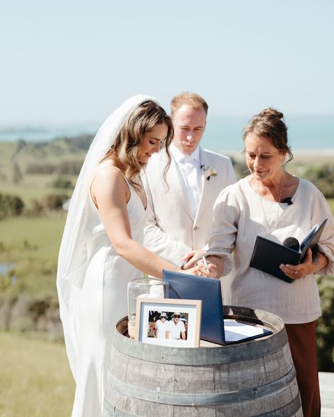 The couple sign the register on a barrel with Tracy beside them