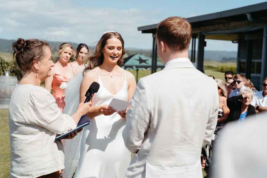 The bride laughs during her vows as Tracy holds the microphone