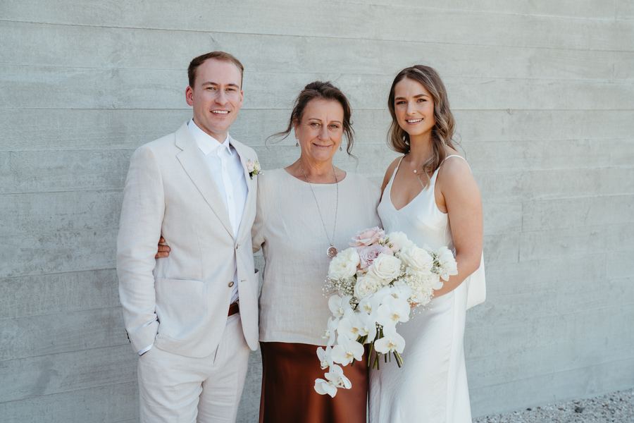 The newly married couple with Tracy in front of a concrete wall